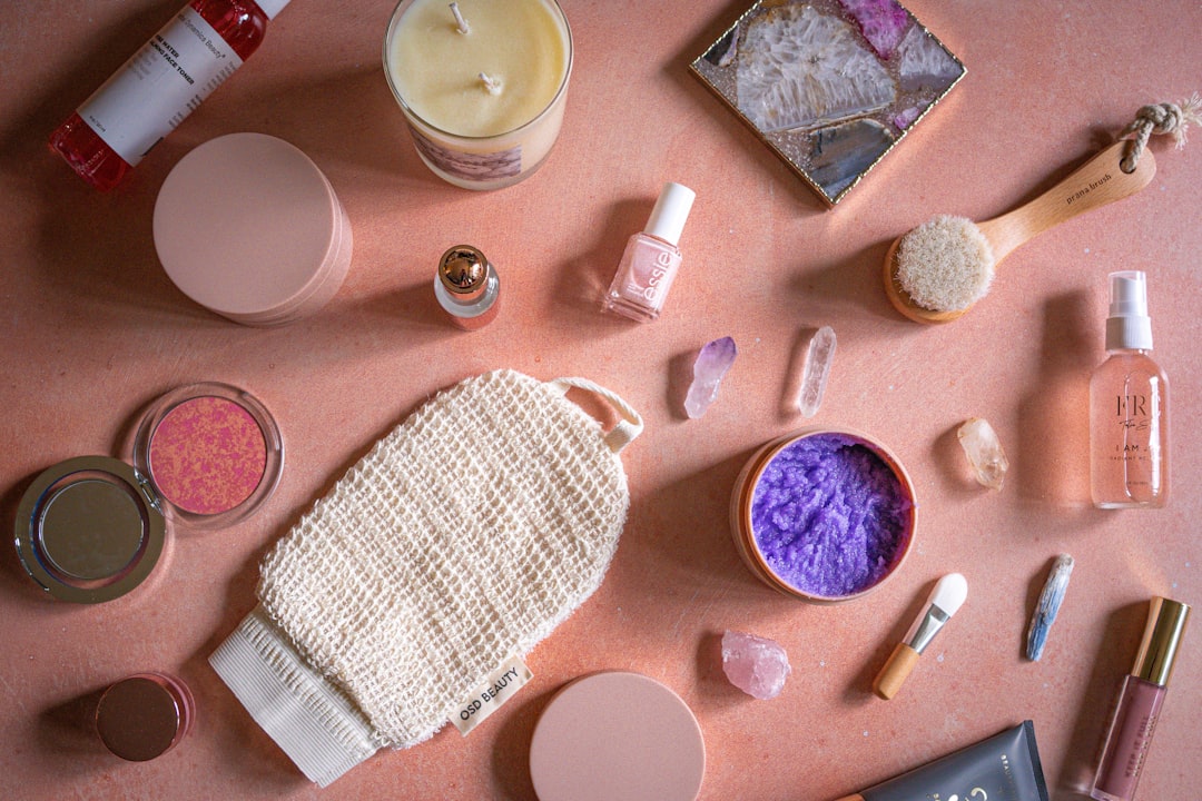 A flat lay of skincare routine products including serums, moisturizers, and cleansers arranged on a pink background
