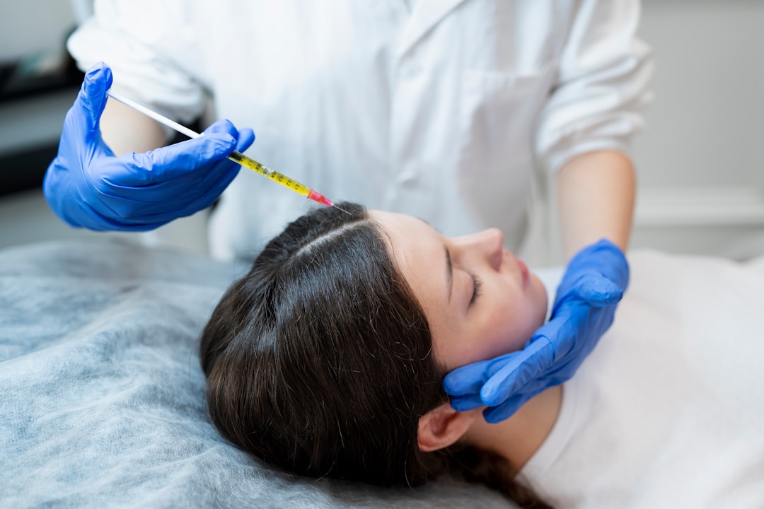 Practitioner in blue gloves performing mesotherapy scalp microinjections for hair restoration