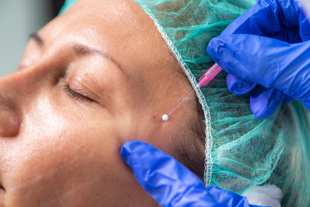 Un praticien en médecine esthétique réalisant un traitement par injections faciales destiné à le rajeunissement de la peau ou à la mésothérapie dans un cabinet médical
