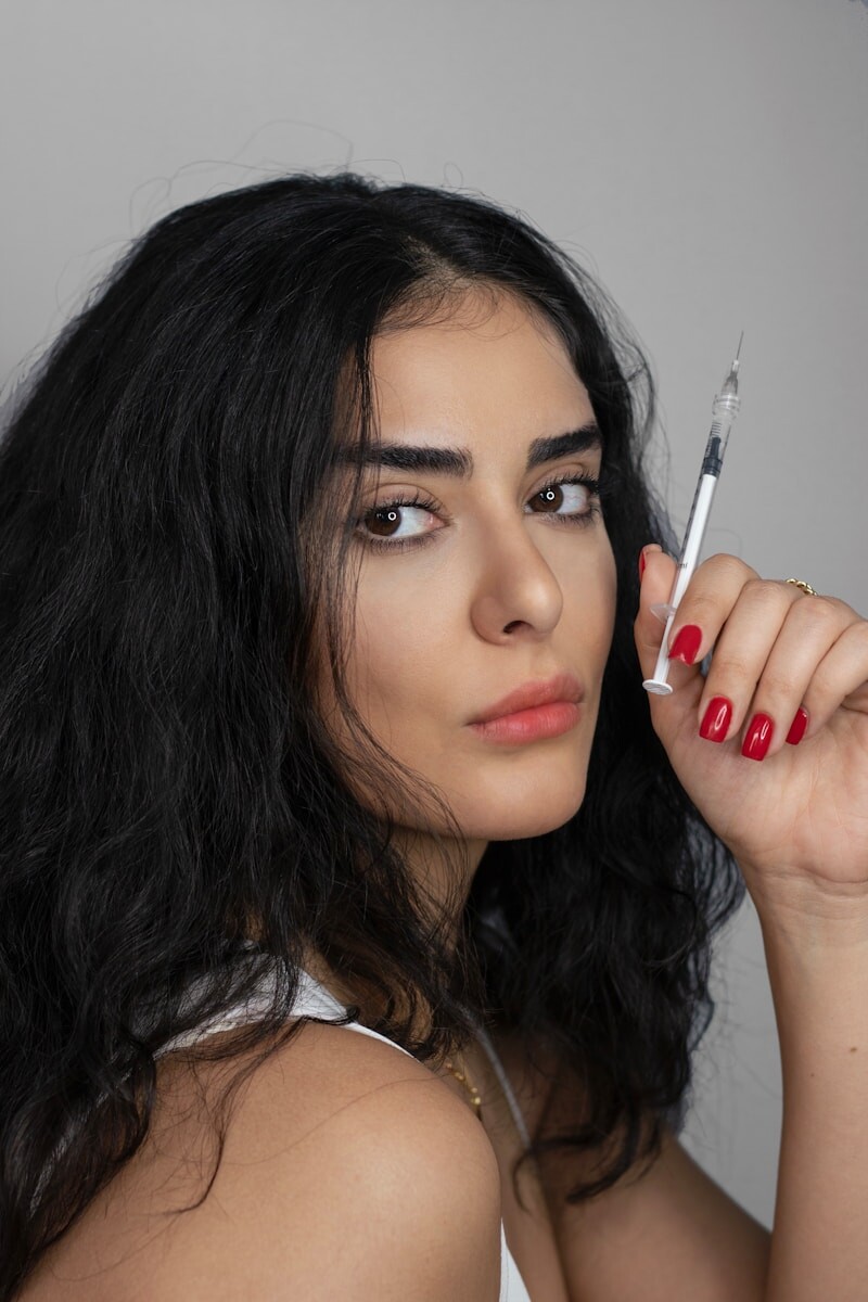 A woman holds a syringe, staring intently.