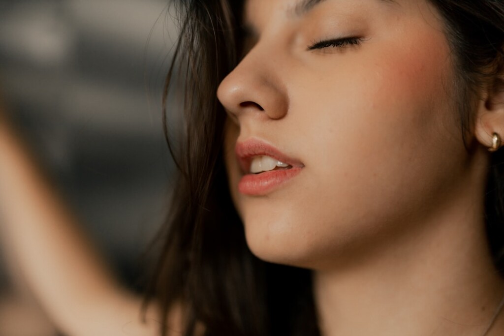 Femme aux yeux fermés, l'air serein et détendu, illustrant l'expérience apaisante d'une consultation et d'un traitement d'augmentation des lèvres dans une clinique esthétique